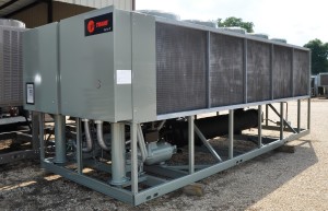 A large Trane industrial chiller unit with metal panels and grille sides is installed outdoors, showcasing robust Industrial Refrigeration Equipment.