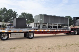 A large Industrial Chiller unit is loaded onto a flatbed trailer, showcasing robust Industrial & Commercial Chillers in a worksite setting.