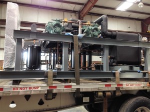 Large industrial chiller unit mounted on a flatbed truck, secured with straps and labeled "DO NOT BUMP"—ideal for industrial chillers use.